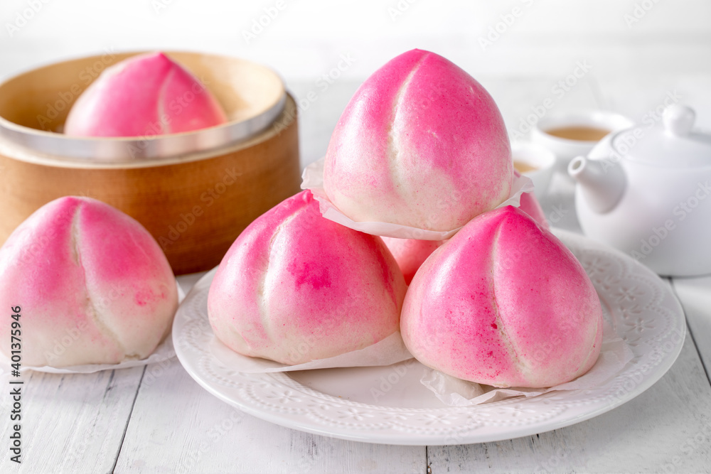 Pink Chinese peach birthday bun food on white table background.