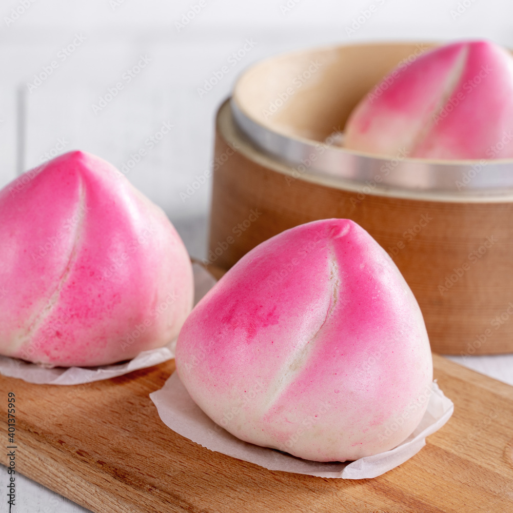 Pink Chinese peach birthday bun food on white table background.