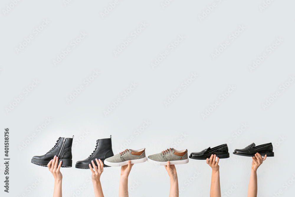 Hands with stylish shoes on white background