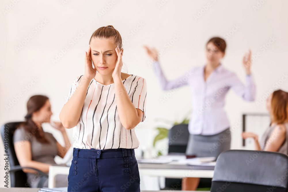 Stressed woman with headache and noisy people in office