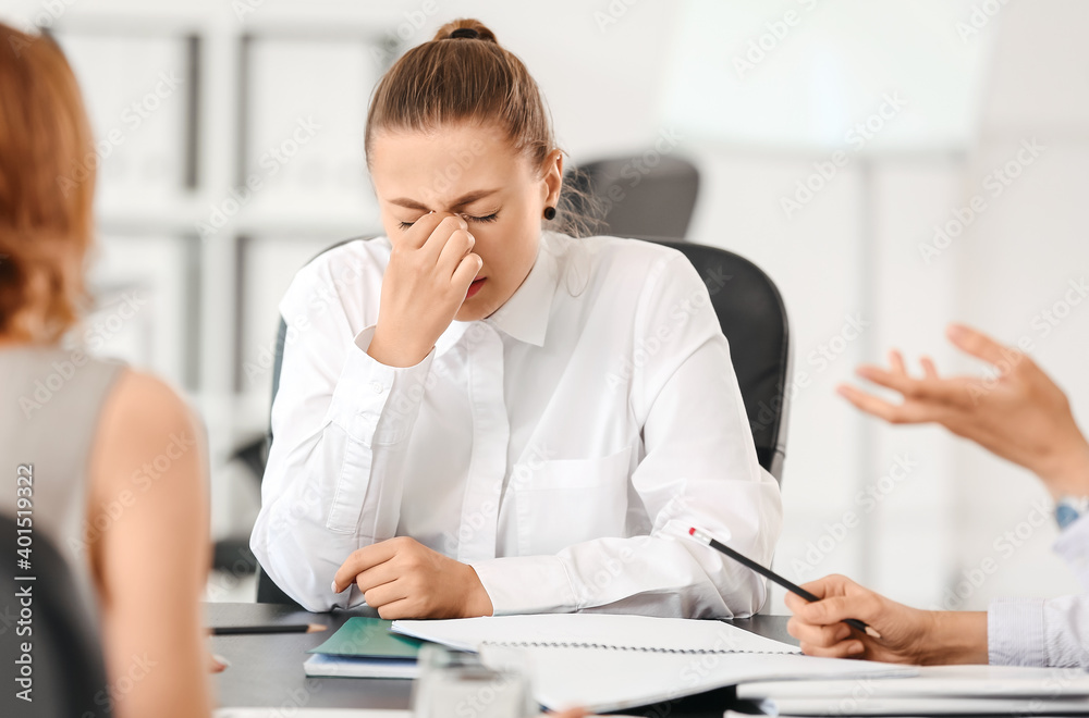 Stressed woman with headache and noisy people in office