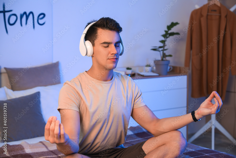 Young man listening to music in bedroom at home