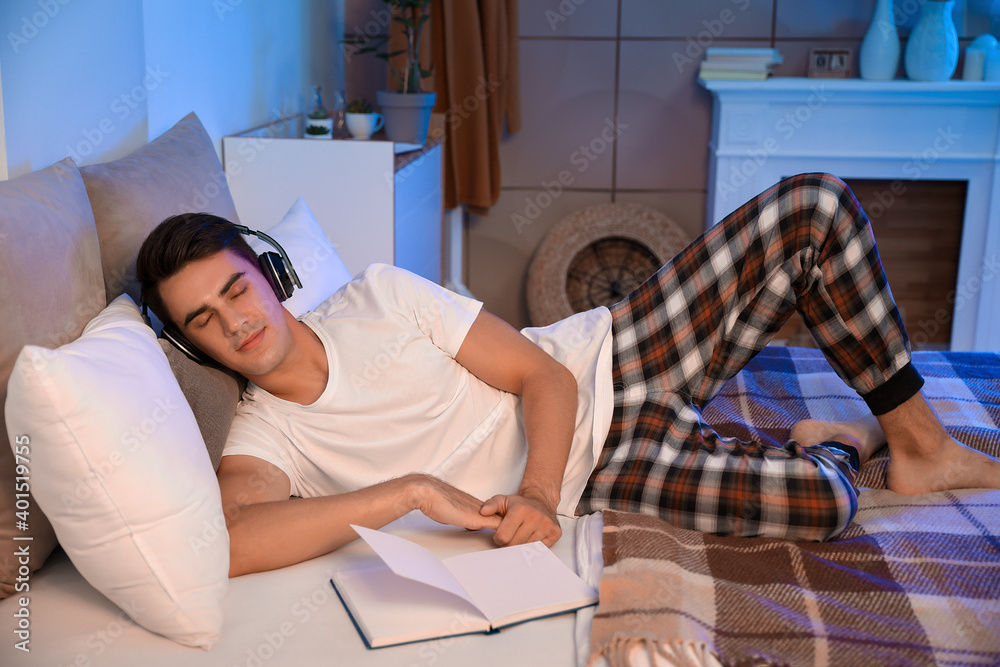 Young man listening to music in bedroom at home