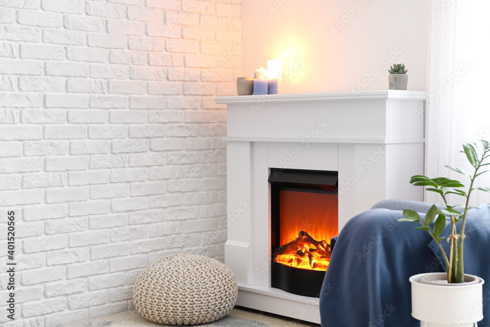 Fireplace with houseplant and pouf in interior of room