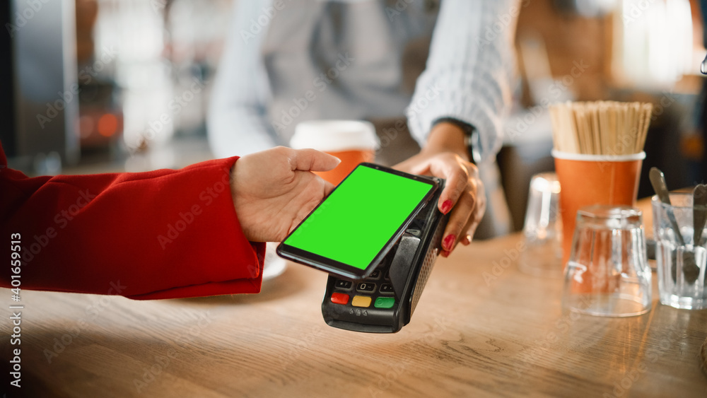 Close Up of a Feminine Hand Holding a Smartphone with Green Screen Template with an NFC Payment Tech