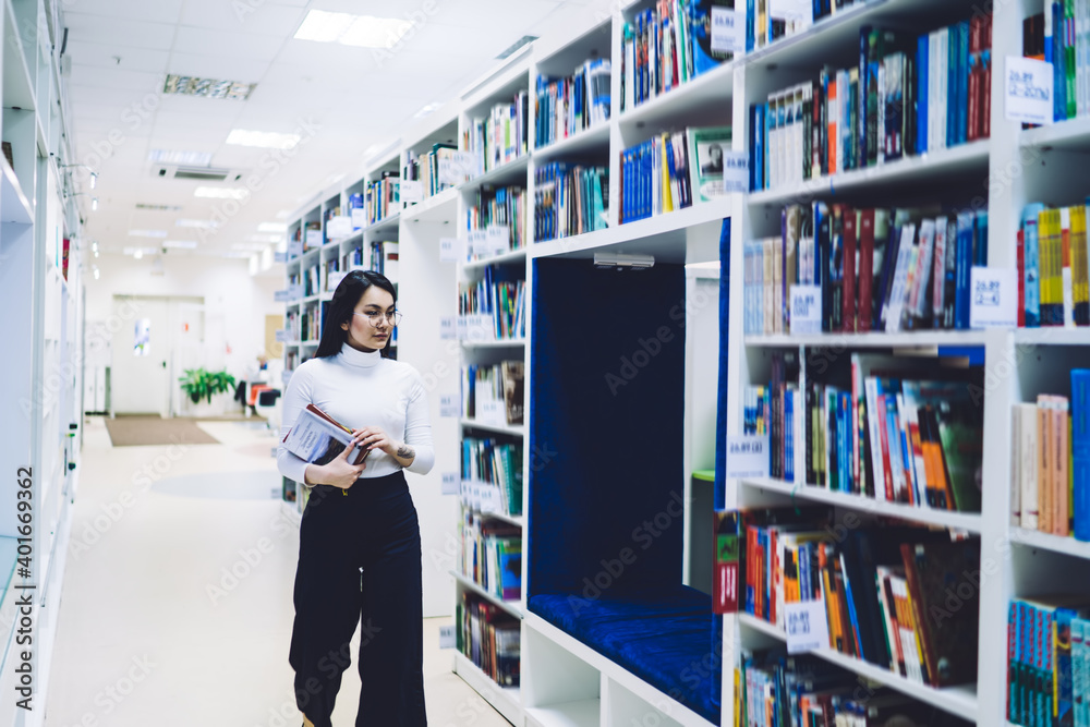 Dark haired woman with books walking in bookstore