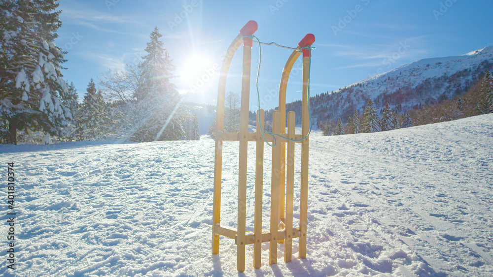 镜头闪光灯：木制雪橇直立在一片白雪皑皑的草地上。