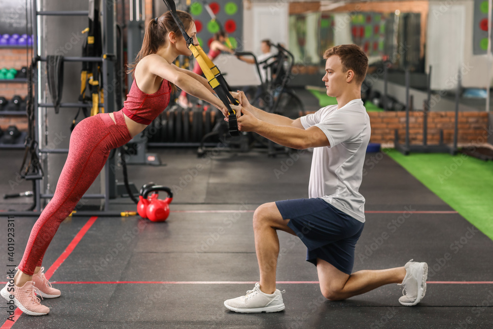 Sporty young woman training with coach in gym