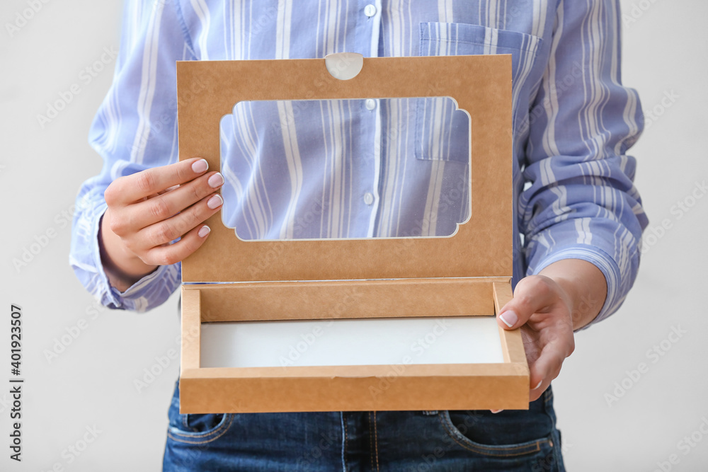 Woman with cardboard box on light background