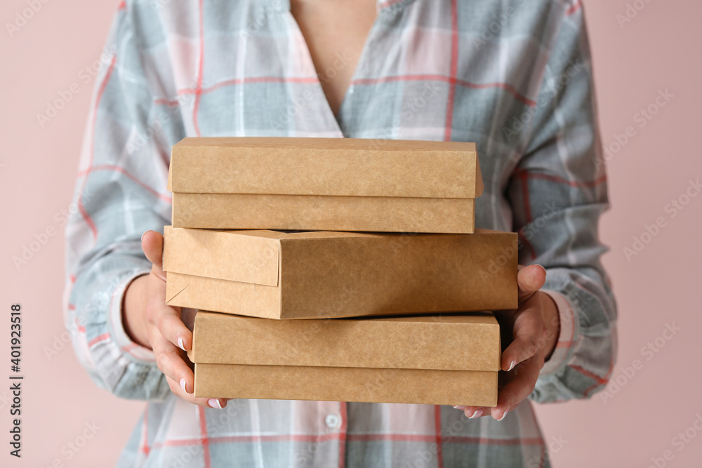 Woman with cardboard boxes on color background