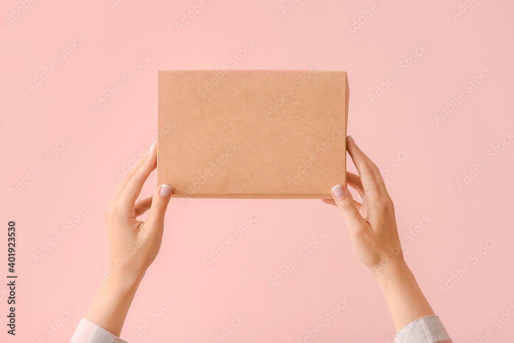 Hands with cardboard box on color background