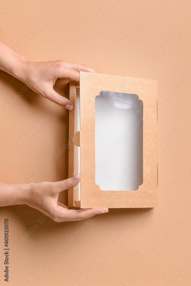 Hands with cardboard box on color background