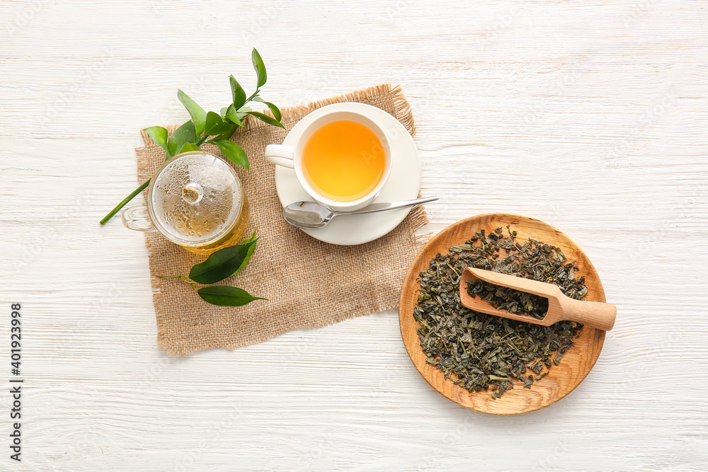 Composition with cup of green tea and dry leaves on table