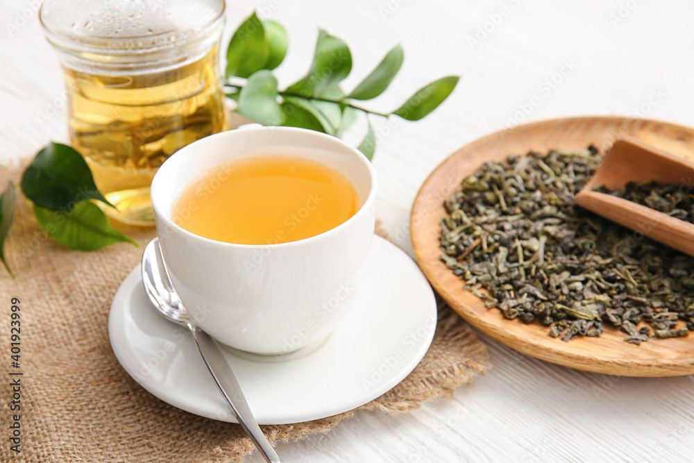 Composition with cup of green tea and dry leaves on table