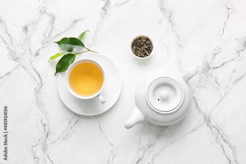 Cup of green tea and teapot on table