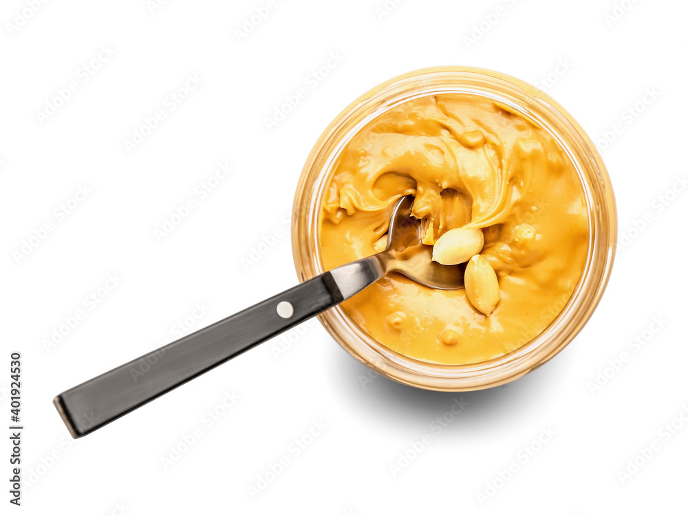 Jar and spoon with tasty peanut butter  on white background