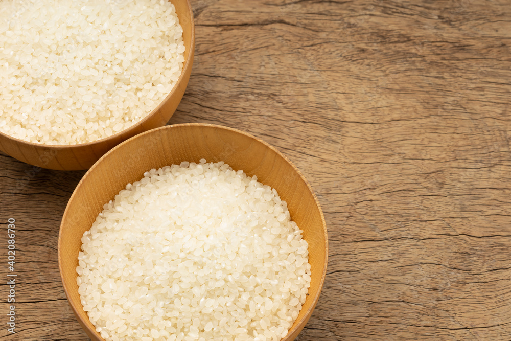 Japanese rice in wooden bowl on texture of wood background