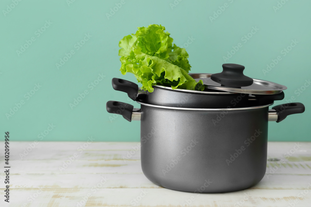 Cooking pots with lettuce on wooden table