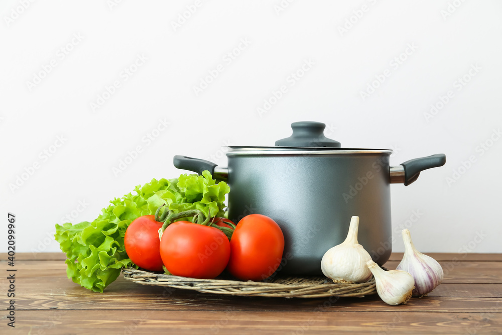 Cooking pot with vegetables on wooden table