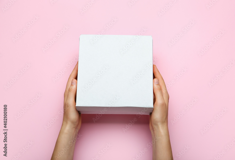 Hands with blank cardboard box on color background