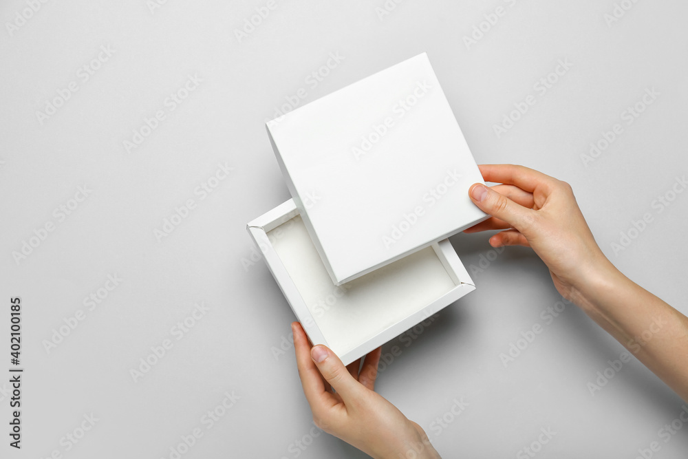 Hands with blank cardboard box on light background