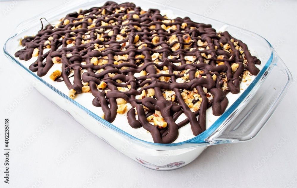 Composition in natural light. Homemade cake with cream, fruit and chocolate. In glassware, on a gray