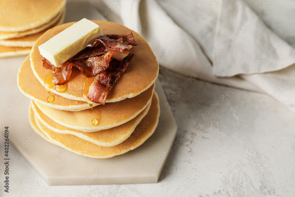 Tasty pancakes with butter and fried bacon on table