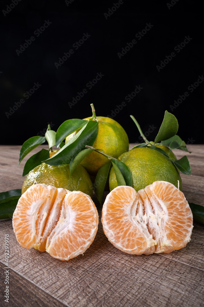 Fresh green tangerine mandarin orange on dark wooden table background.