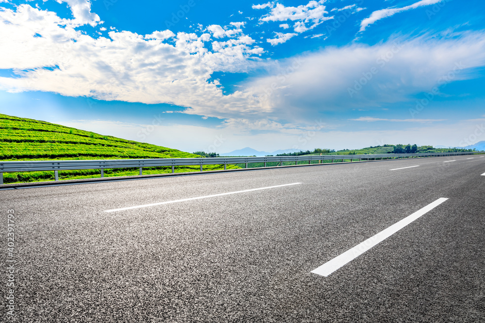 Asphalt road and mountain with tea plantation under blue sky.Road and mountain background.