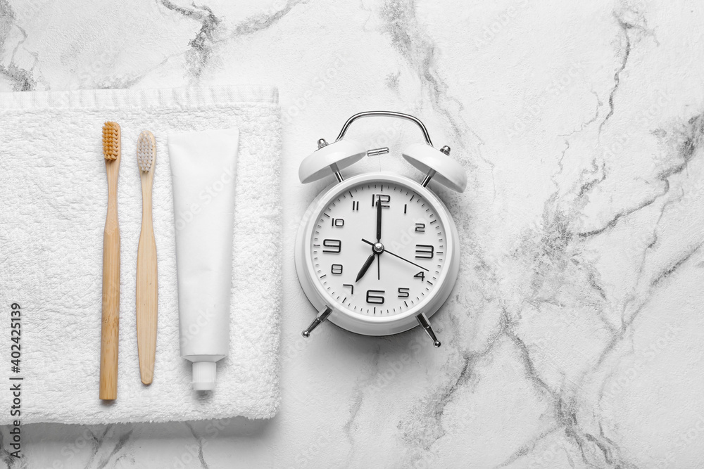 Alarm clock, paste and toothbrushes on table