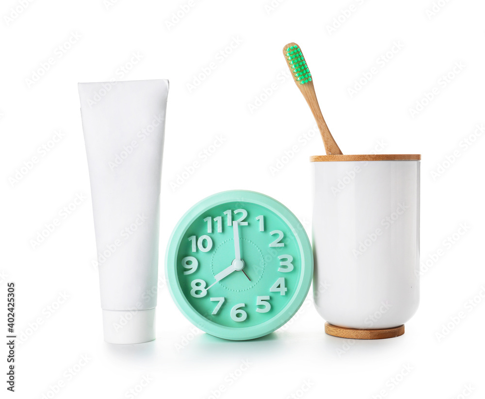 Alarm clock, paste and toothbrush on white background