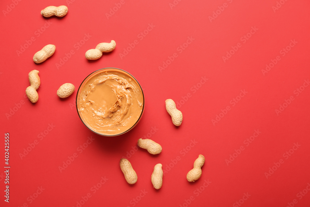 Bowl with tasty peanut butter and nuts on color background