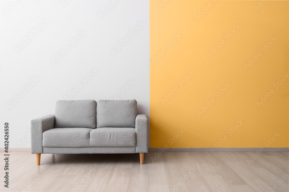 Stylish cozy sofa near color wall