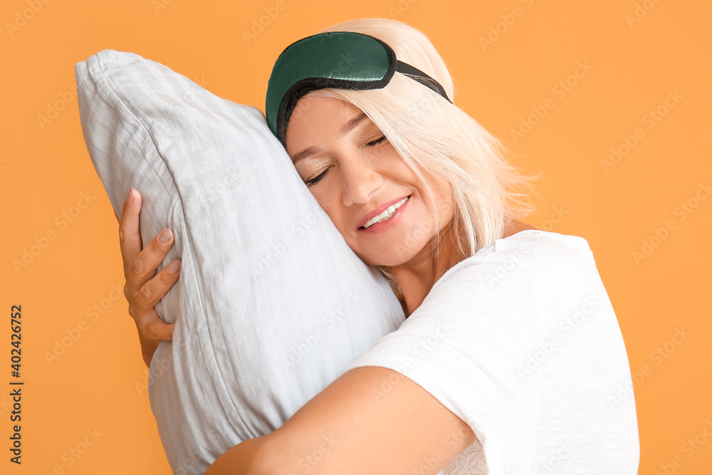 Mature woman in sleep mask on color background