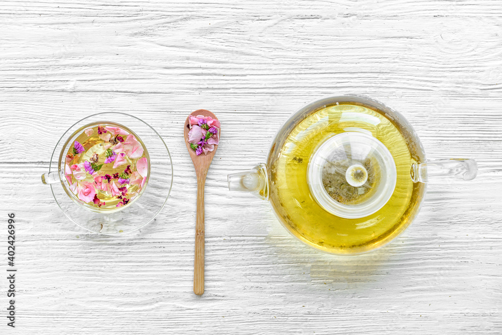 Teapot and cup with floral tea on light background