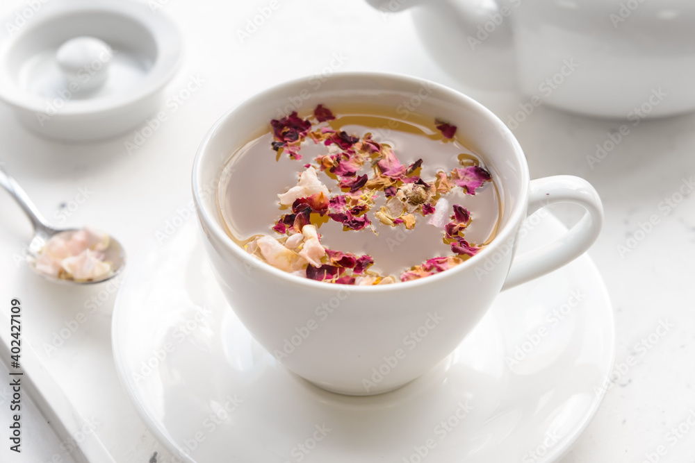 Cup with floral tea on light background