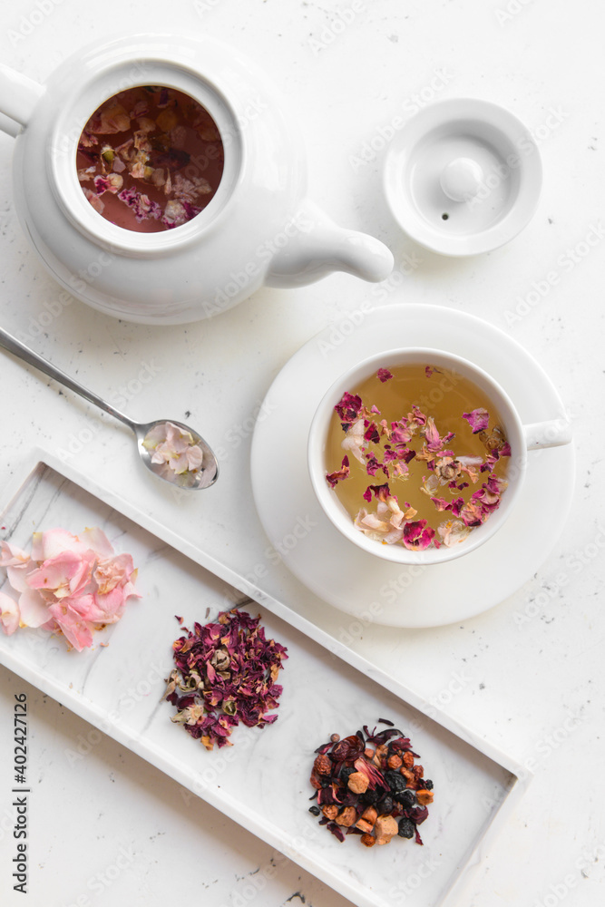 Dry flowers, teapot and cup with floral tea on light background