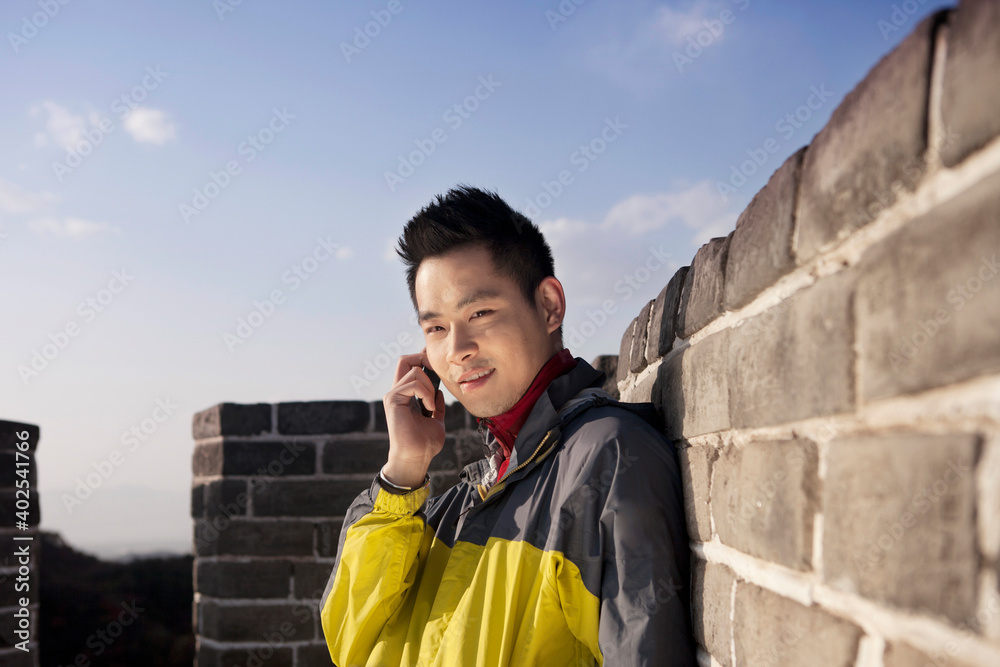 一个年轻人在长城旅游中使用手机