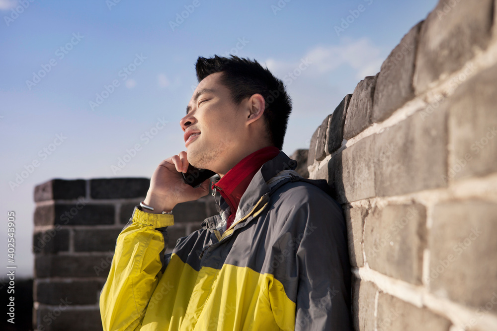 A young man use the mobile phone in the Great Wall Tourism 