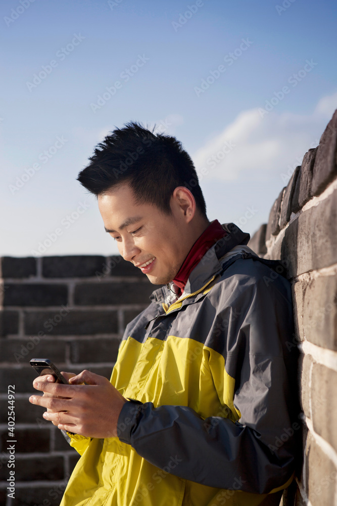 A young man use the mobile phone in the Great Wall Tourism 