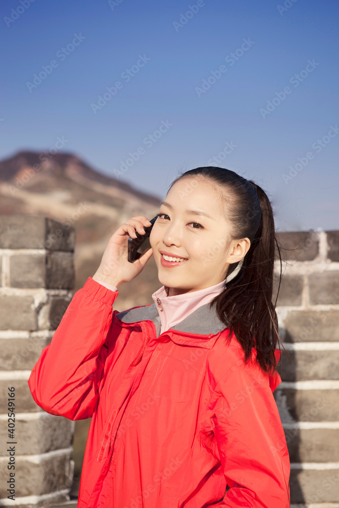 一名年轻女子在长城旅游中使用手机