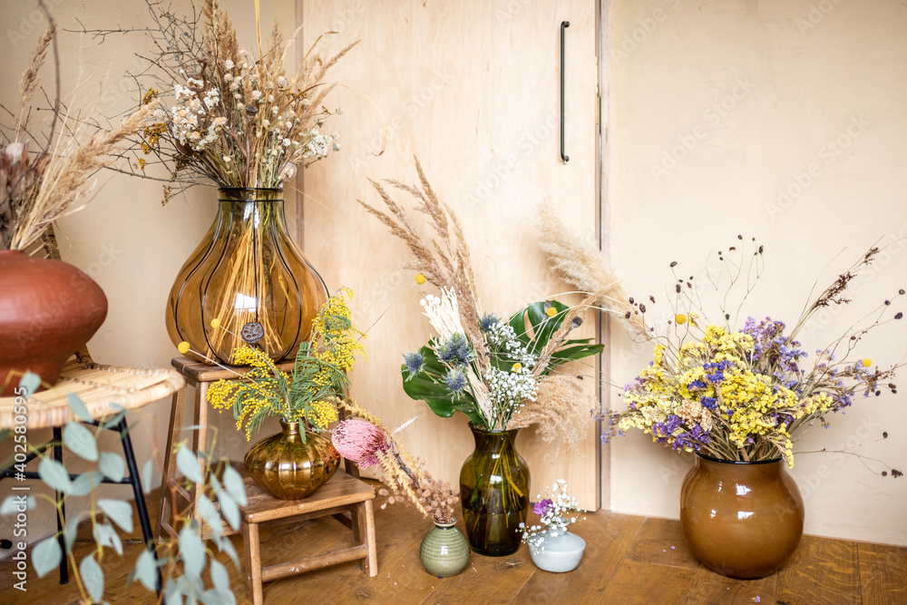 Variety of different compositions of dried and fresh flowers and herbs in a room with beige walls