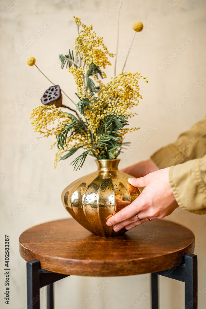 米色墙上的金色花瓶里有鲜花和香草的女性装饰家居