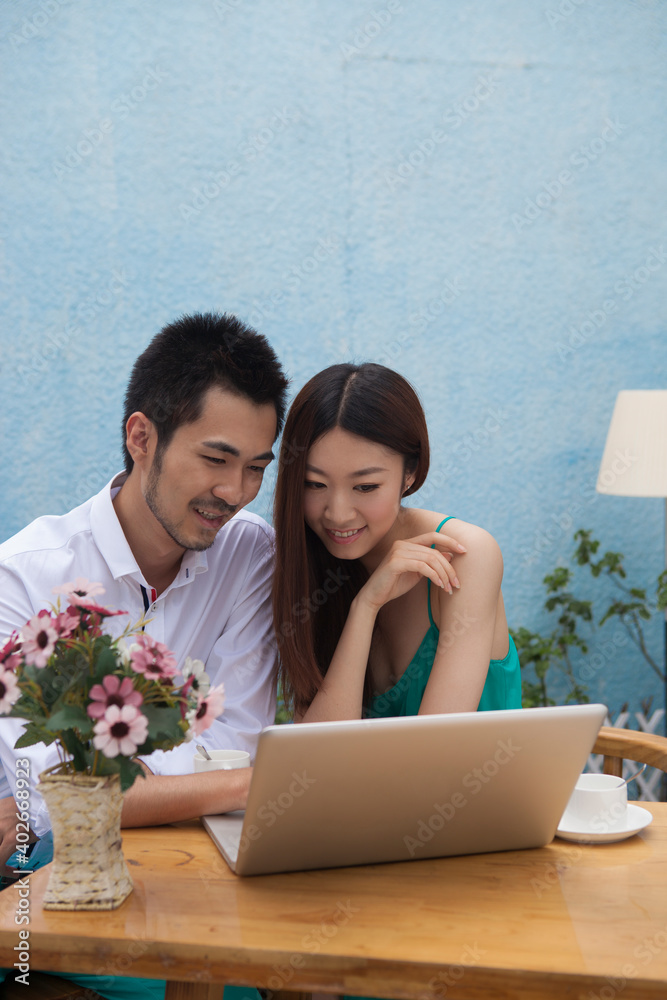 A young couple are using a computer 