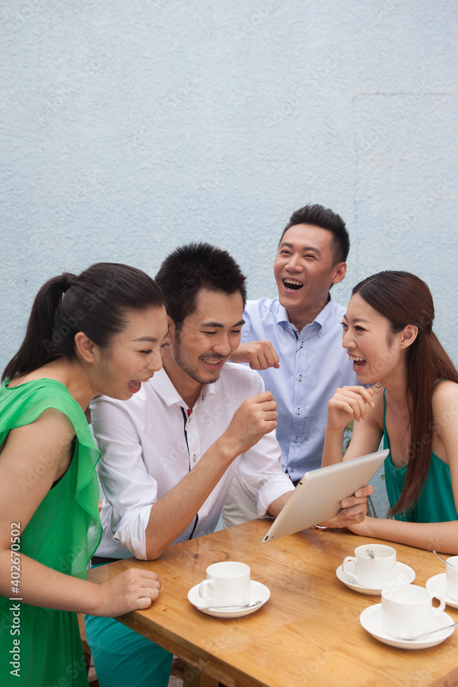 Four people sit together working on a tablet