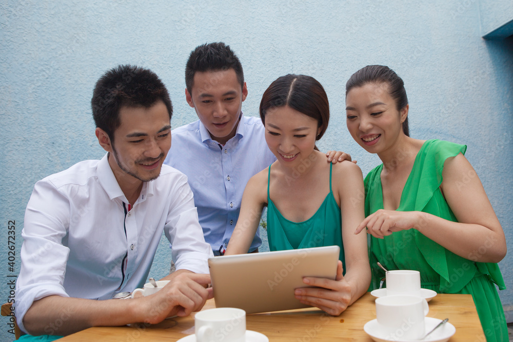 Four people sit together working on a tablet