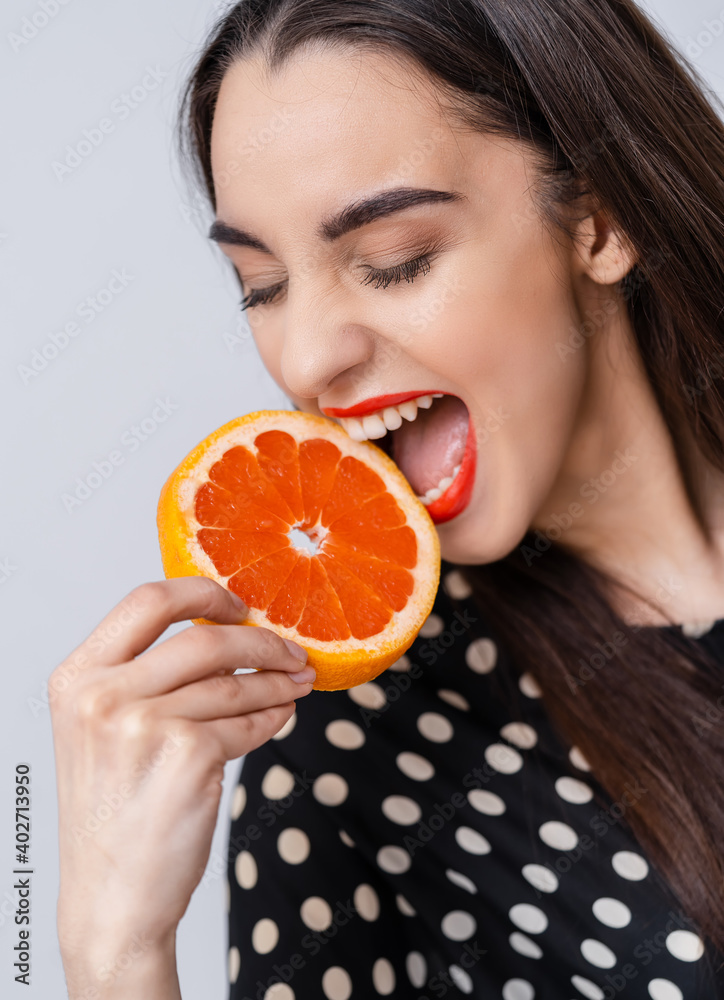 Young beautiful woman smiling with slices of oranges in hand over white background. Happy healthy sk