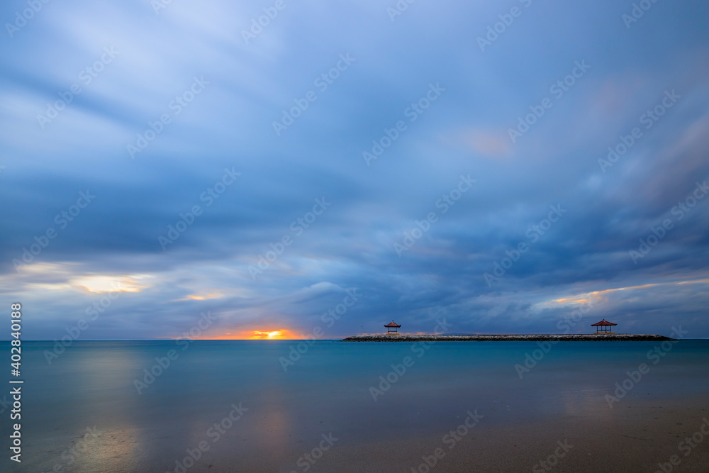 Beautiful sunrise on Bali in Sanur by the sea with a view over the beach to the sea. a temple and br