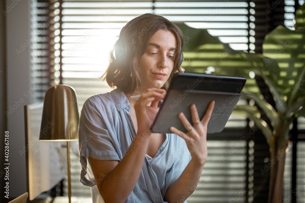 Portrait of a confident woman works on a touchpad at cozy home office with a green plant on the back