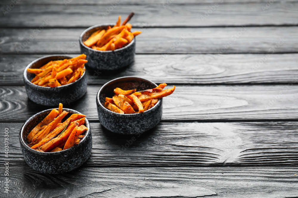 Bowls with tasty cooked sweet potato on wooden background